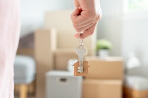 Moving,House,,Relocation.,Woman,Hold,Key,House,Keychain,In,New